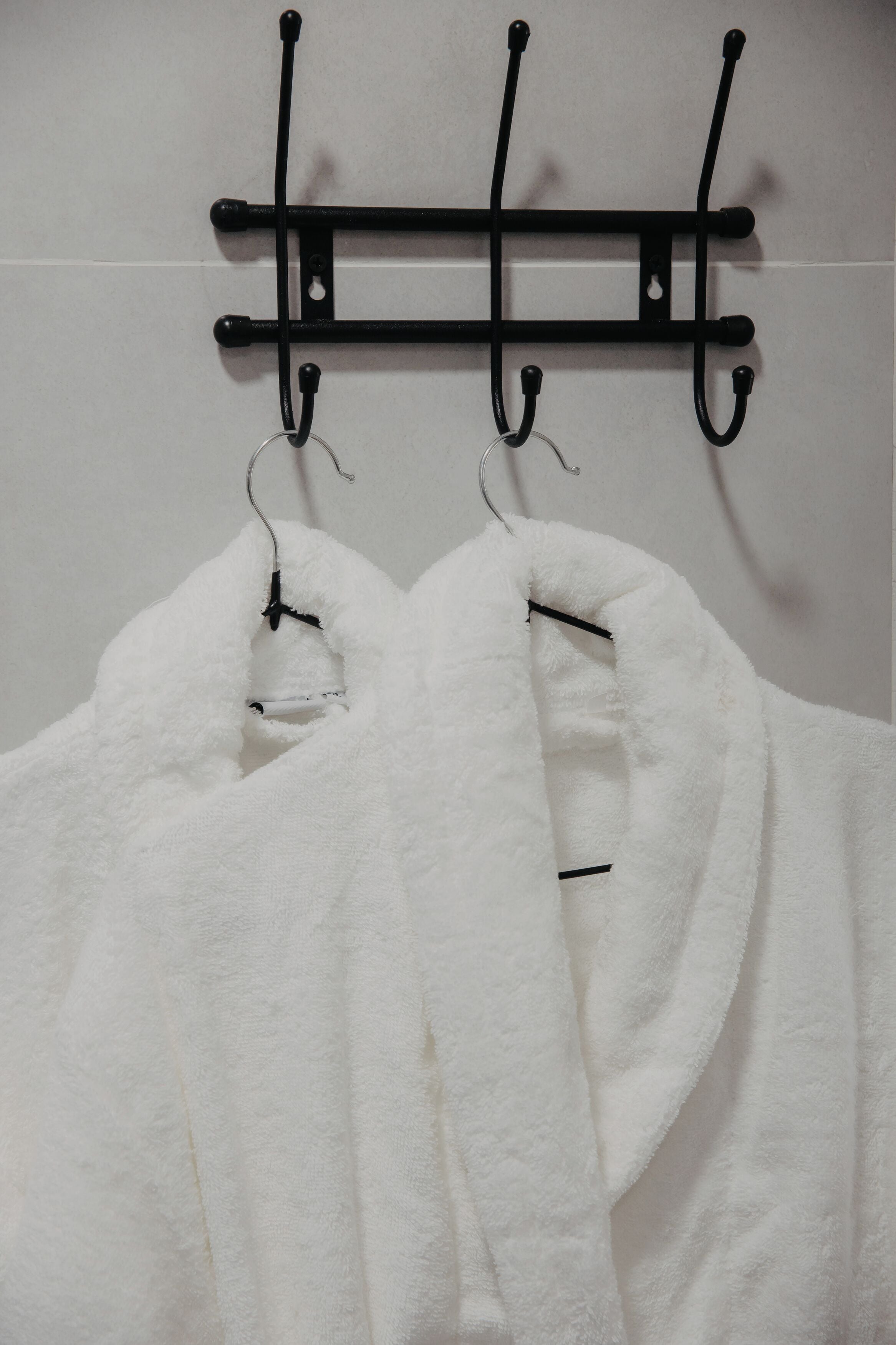 A white towel hanging on a black towel rack in a bathroom.