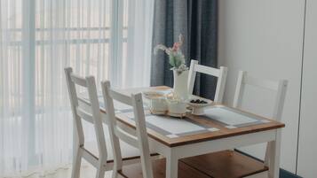 A dining area with a wooden table, white chairs, and a vase with flowers.