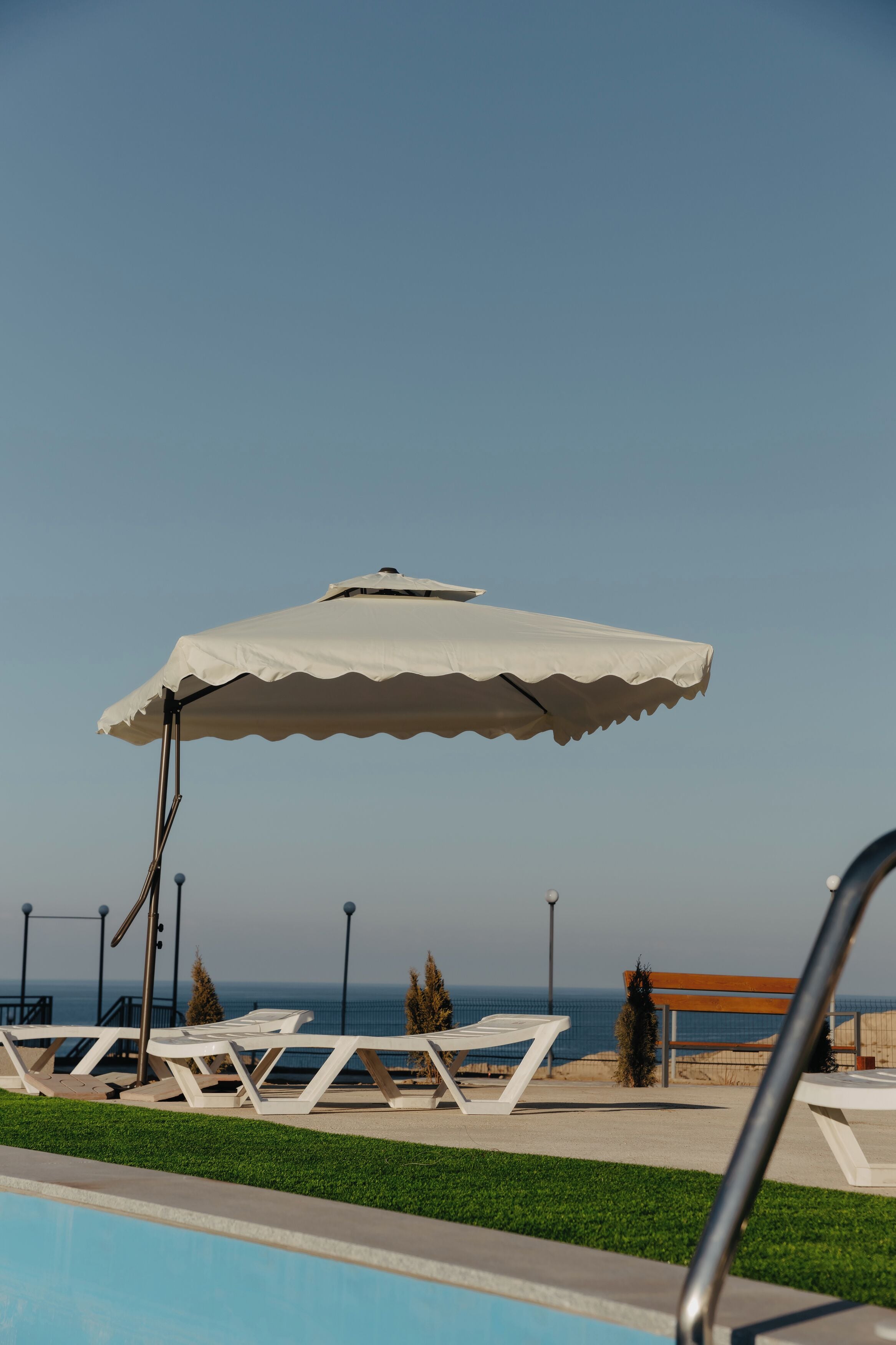 Zona de piscina con sillones de descanso y una pérgola.