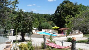 Un espace piscine avec un petit bâtiment, un hamac et un lampadaire.