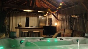 Un bain à remous dans un chalet rustique, avec un coin bar et un téléviseur.