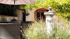 Un espace extérieur aménagé avec des chaises en osier et un grand parasol.