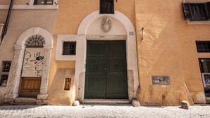 Un edificio con una porta verde a due ante, un ingresso ad arco e una piccola finestra sopra la porta.