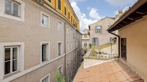Stretto vicolo tra edifici con tetti in tegole di terracotta e cielo sereno.