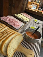Una mesa con pan en rodajas, diferentes carnes y un tazón de salsa de tomate.