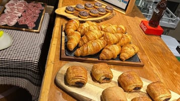 A breakfast buffet with various pastries, including croissants and chocolate-filled pastries, and a selection of meats and cheeses.