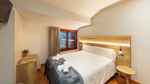 A hotel room with a bed, bedside table, and a window with curtains. - Hotel Restaurant Camp del Serrat (Escaldes-Engordany)