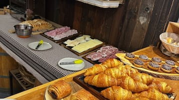 A breakfast buffet with pastries, meats, and condiments.
