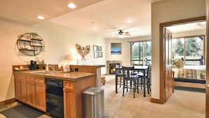 A kitchen with wooden cabinets, a dishwasher, and a granite countertop. There is a dining area with a table and chairs, and a fireplace.