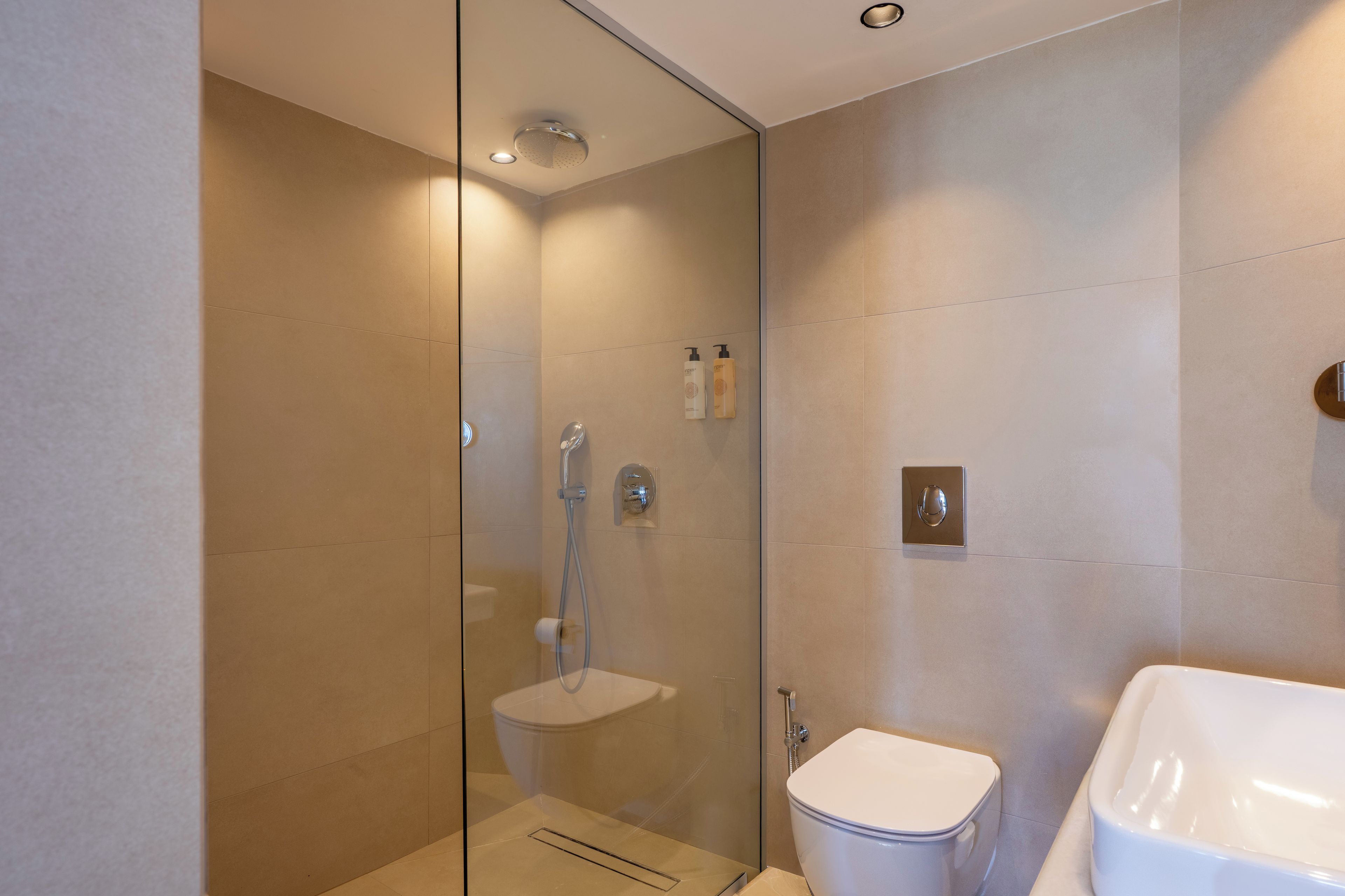 A modern bathroom with a glass-enclosed shower, a white toilet, and a sink.