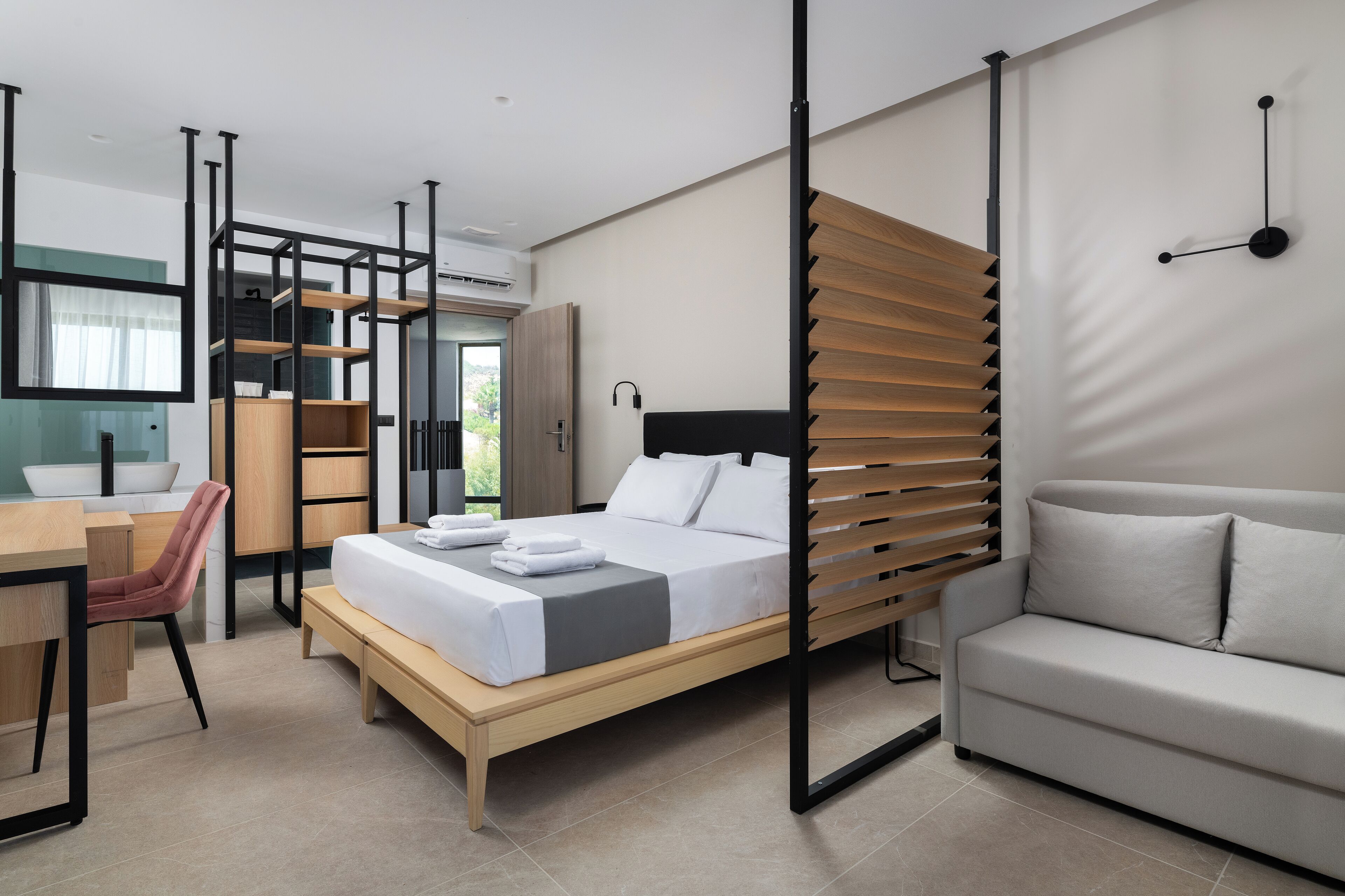 A modern hotel room with a bed, a sofa, a desk, and a chair.