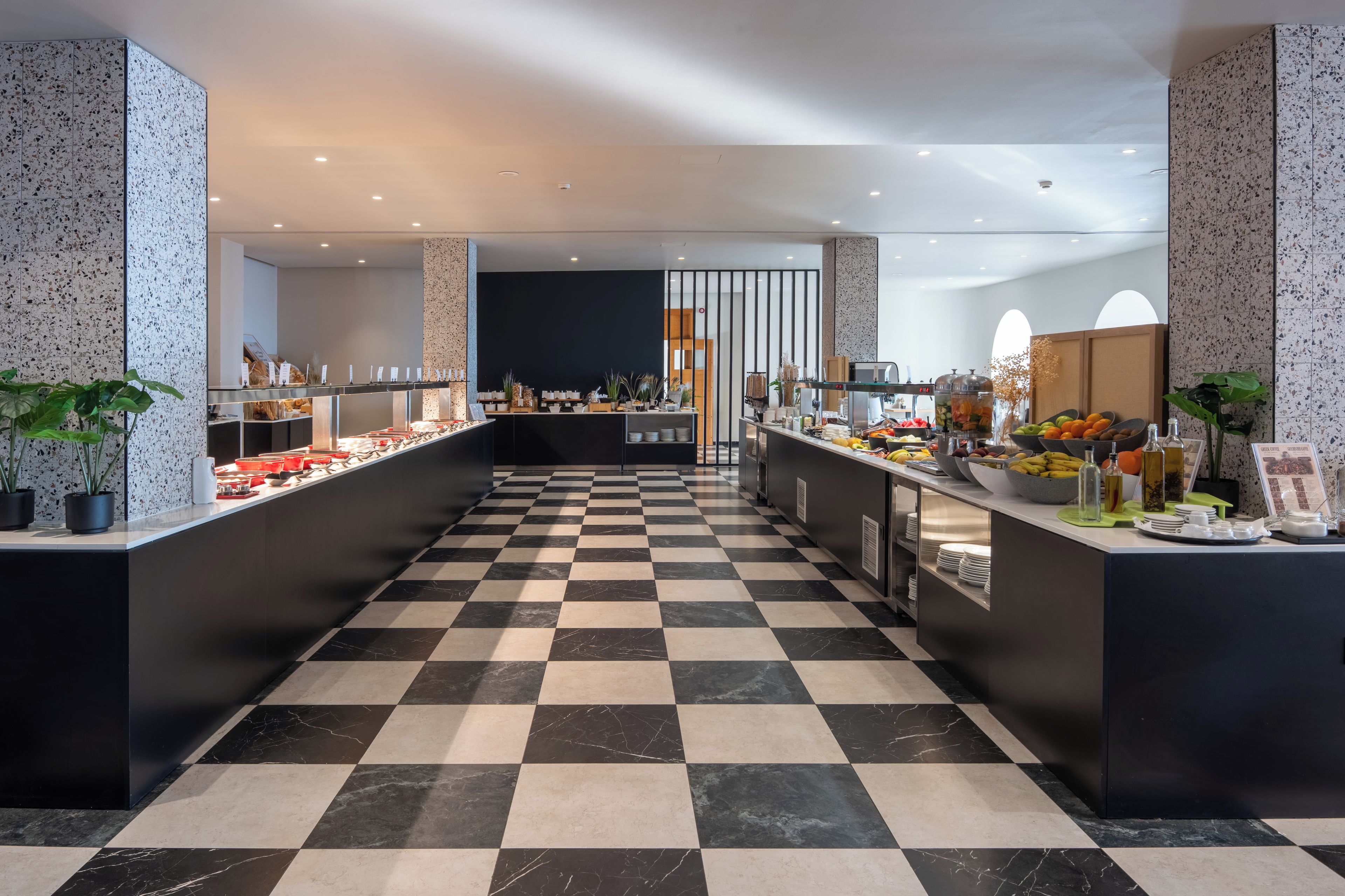 A modern buffet area with a checkered floor, multiple food stations, and a central serving counter.