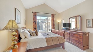 A bedroom with a bed, dresser, and a television on a stand.