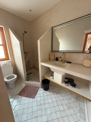 A bathroom with a toilet, shower, sink, and mirror. - Riad Madinina (Marrakech)