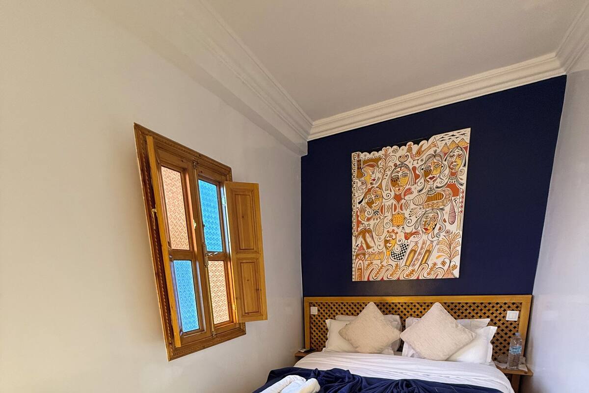 Une chambre à coucher avec un lit, une chaise, une fenêtre et un tapis.