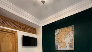 A bedroom with a bed, a television, a decorative wall piece, and a wooden door. - Riad Madinina (Marrakech)