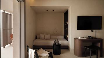 A modern hotel room with a sofa bed, a small desk, a TV, and a chair.