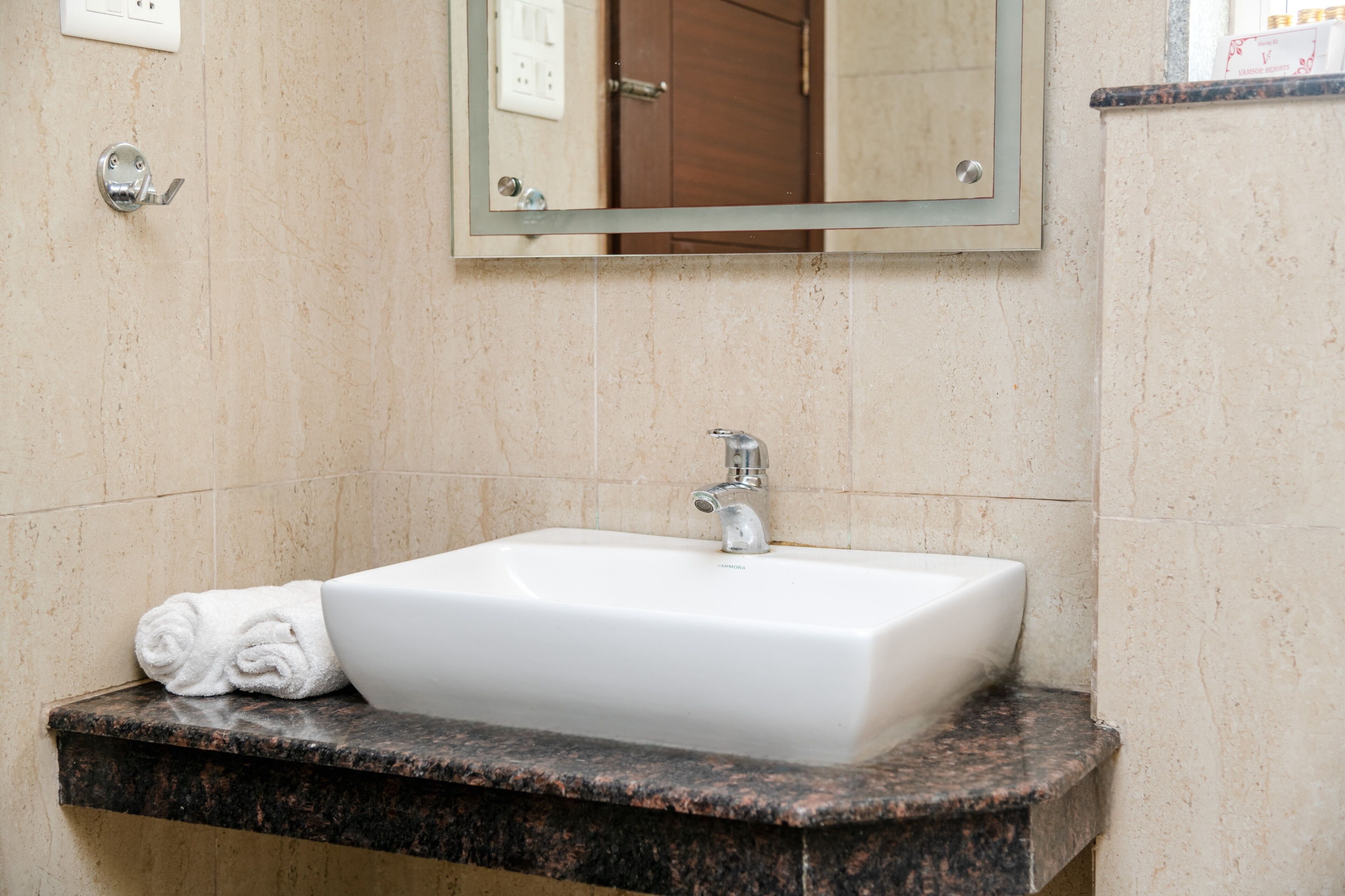 A bathroom with a white sink, a towel, and a mirror.