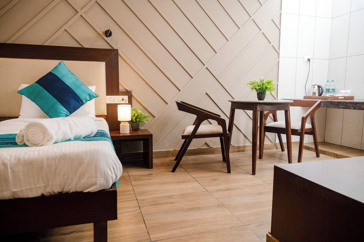 A neatly arranged bedroom with a bed, bedside table, and a small table with a plant.