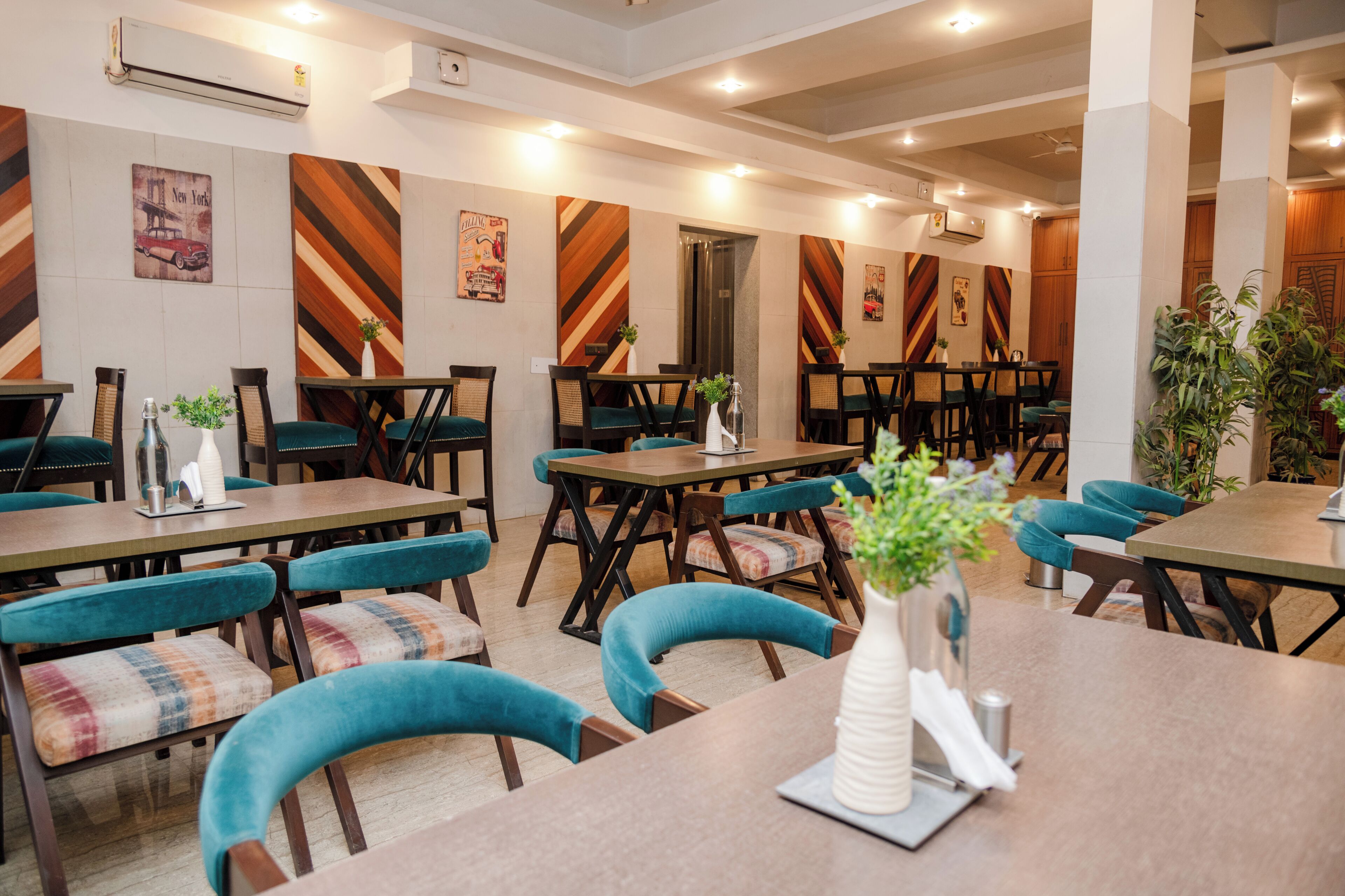 A restaurant with multiple tables and chairs, some with plants on them.