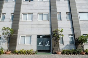 Stylish building with a symmetrical facade and grid-patterned windows, featuring a double entrance and lush greenery.
