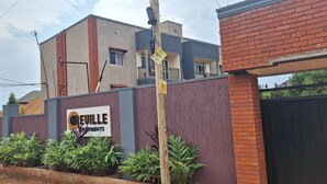A building with a sign for Creuille Investments, surrounded by a low wall and plants. - Oreville Apartments Namugongo Seeta Rd (Seeta)