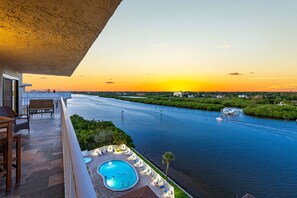 A pool area with lounge chairs and a view of a river at sunset. - 🐬Amazing Penthouse Views🏖️Quick Walk to Beach🌴Bayshore Yacht and Tennis Club (Indian Shores)