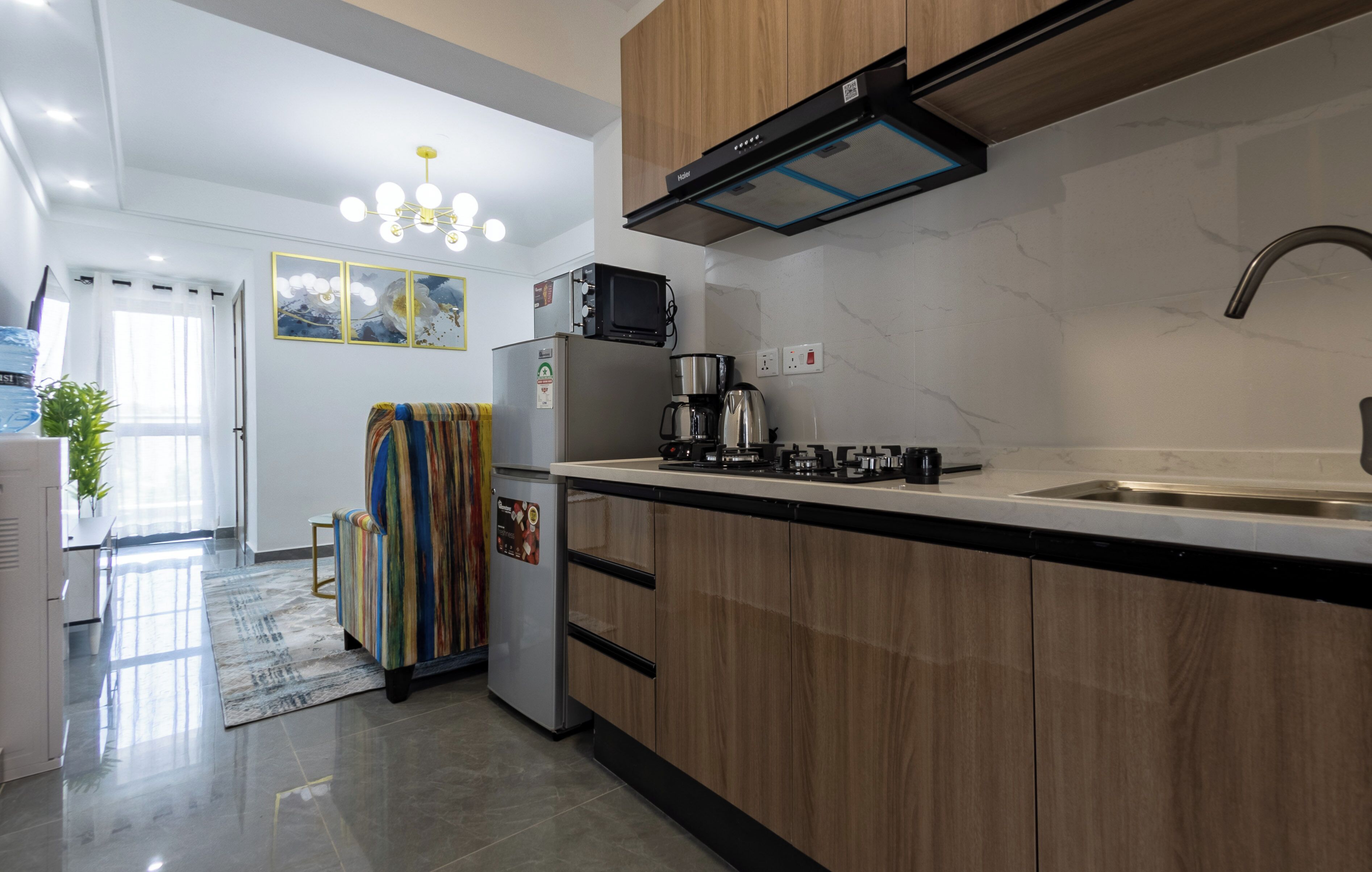 Una cocina moderna con armarios de madera, un lavamanos de acero inoxidable y un microondas integrado.