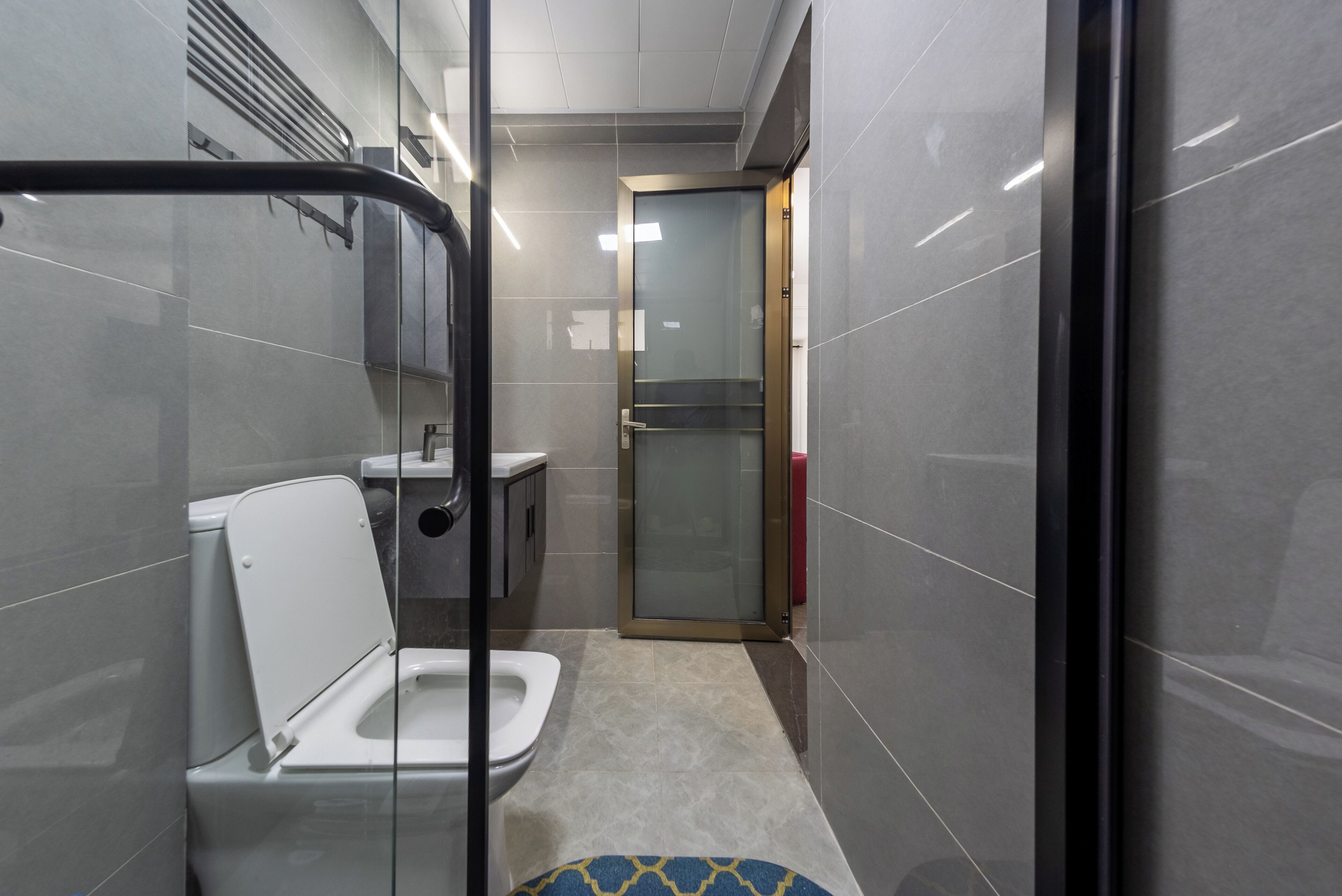 Une salle de bain moderne équipée de toilettes, d’un lavabo et d’une douche à parois en verre.