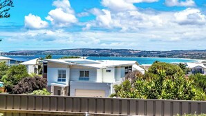 Zona residencial con casas, cielo despejado y una vista distante de la costa.