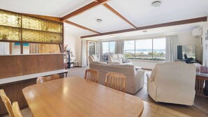 Amplia sala de estar con una mesa de comedor de madera, asientos cómodos y ventanas grandes que ofrecen vistas.