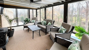 A sunroom with wicker furniture, large windows, and a ceiling fan. - Luxury 6,000+ sq ft Hideaway with Heated Pool, Spa, & Sauna - near Greenville (Taylors)