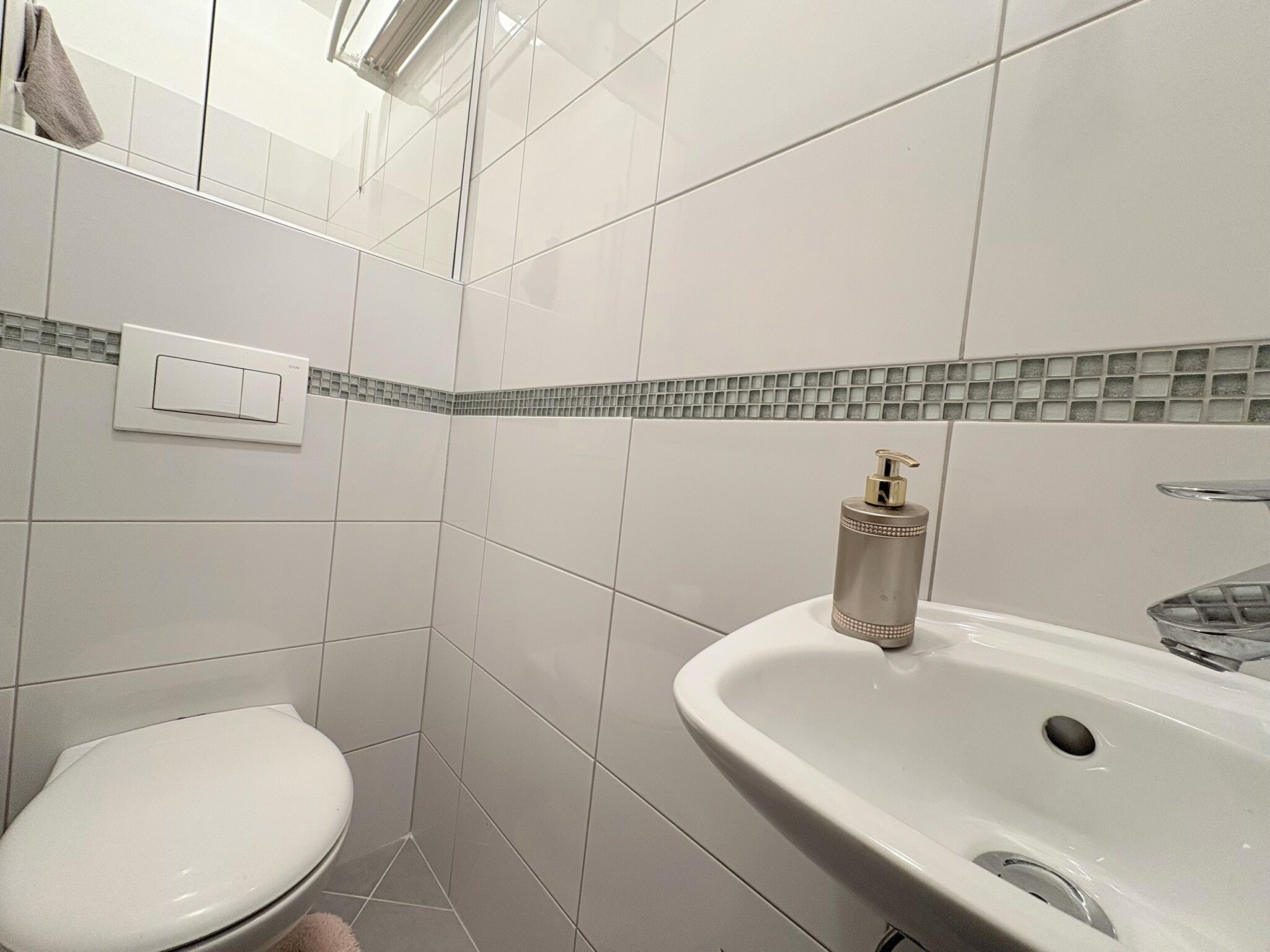 Ein Badezimmer mit Toilette, Waschbecken und einem Lichtschalter an der Wand.