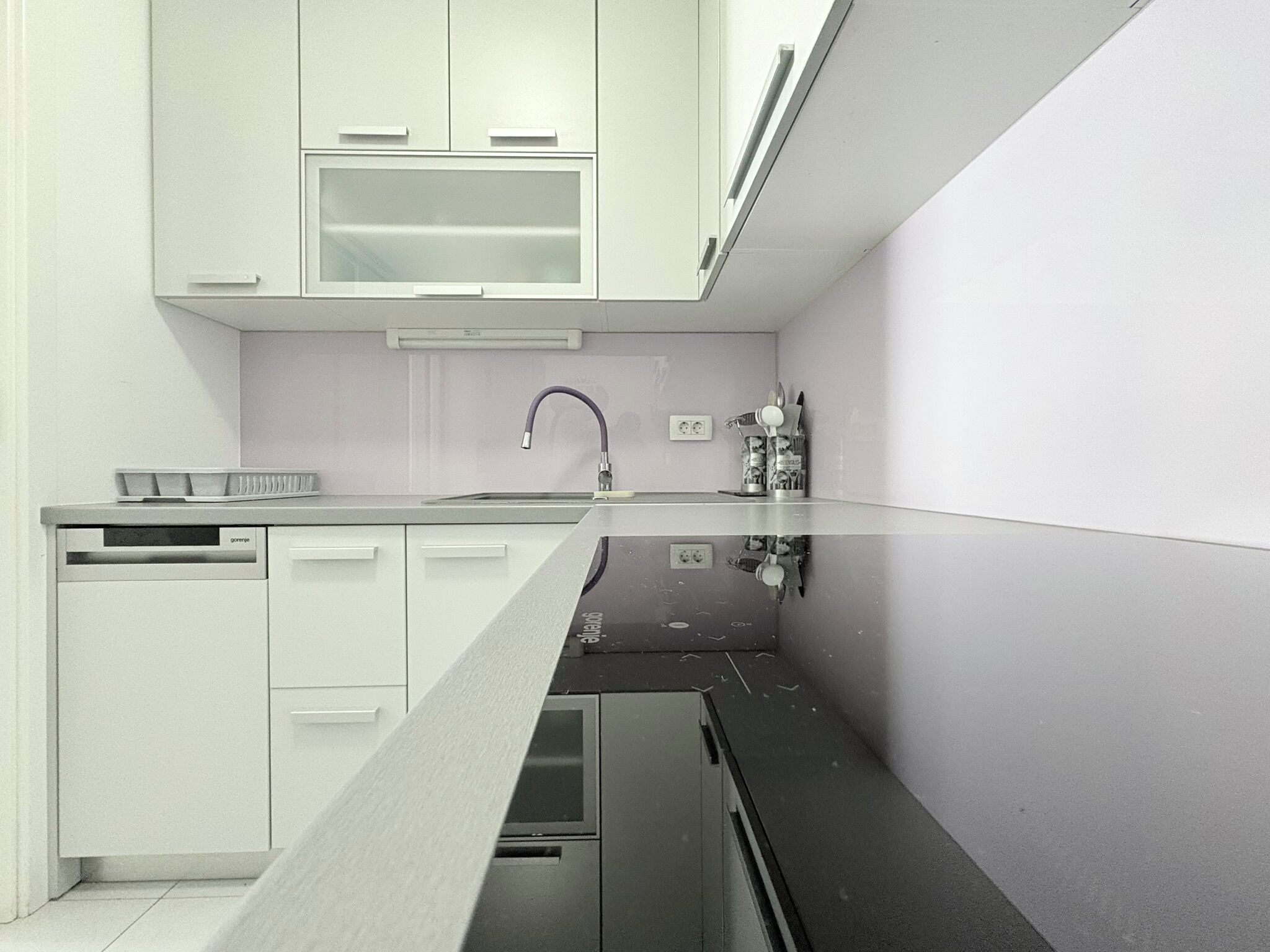 A modern kitchen with white cabinets, a black countertop, and a stainless steel sink.