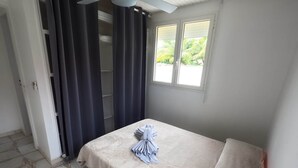 A bedroom with a bed, a window, and a door.
