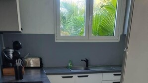 A kitchen with a central island, a sink, and a window with a view of greenery.