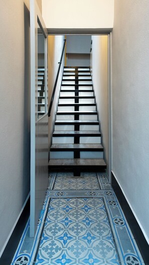 Stairwell leading to an upper level with a handrail and patterned tile floor.