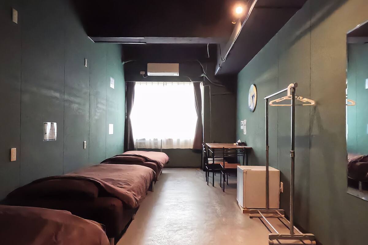 A narrow room with bunk beds, a desk, and a mirror.