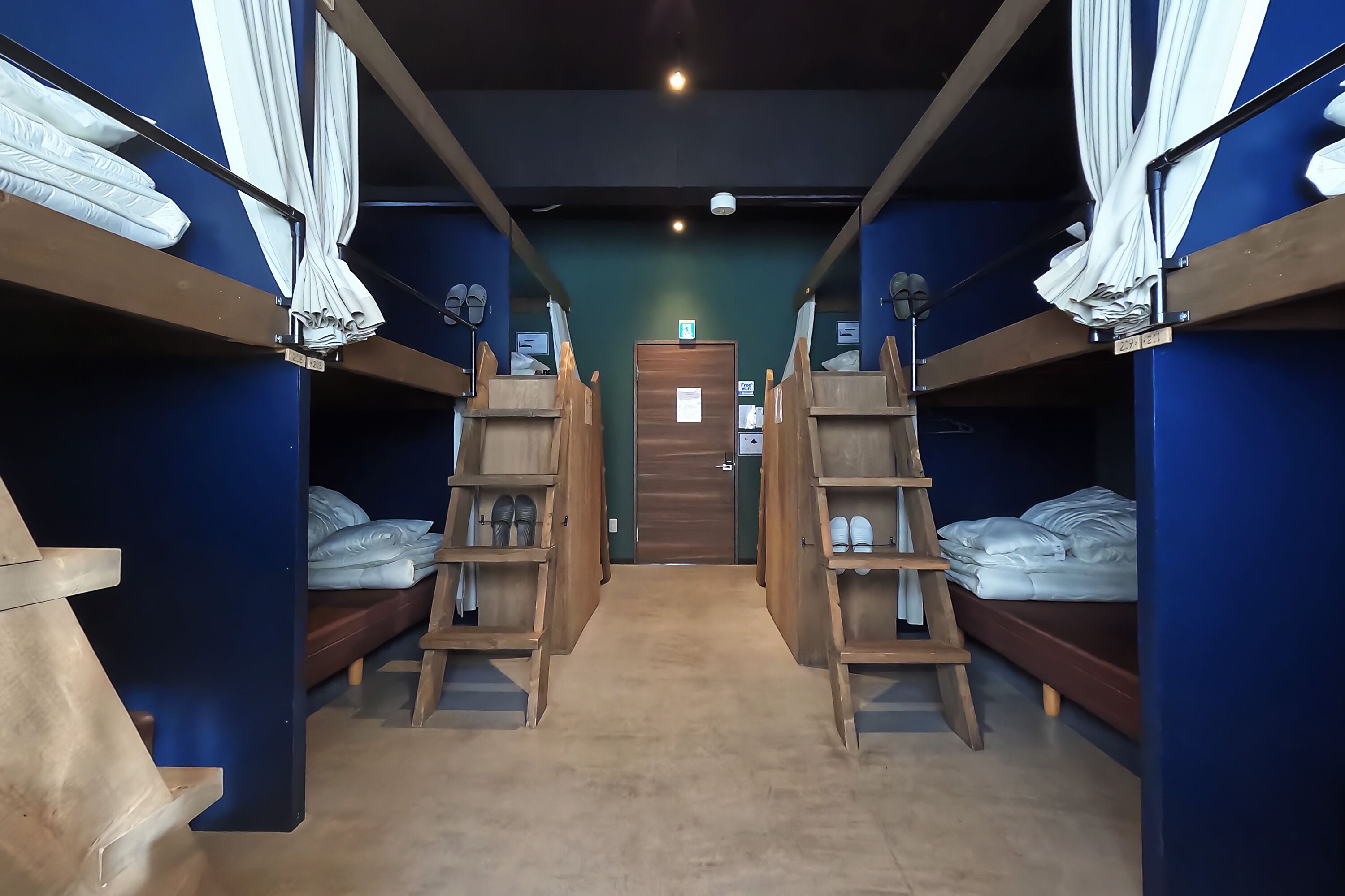 Una habitación con literas, estantes de madera y una puerta en el centro.