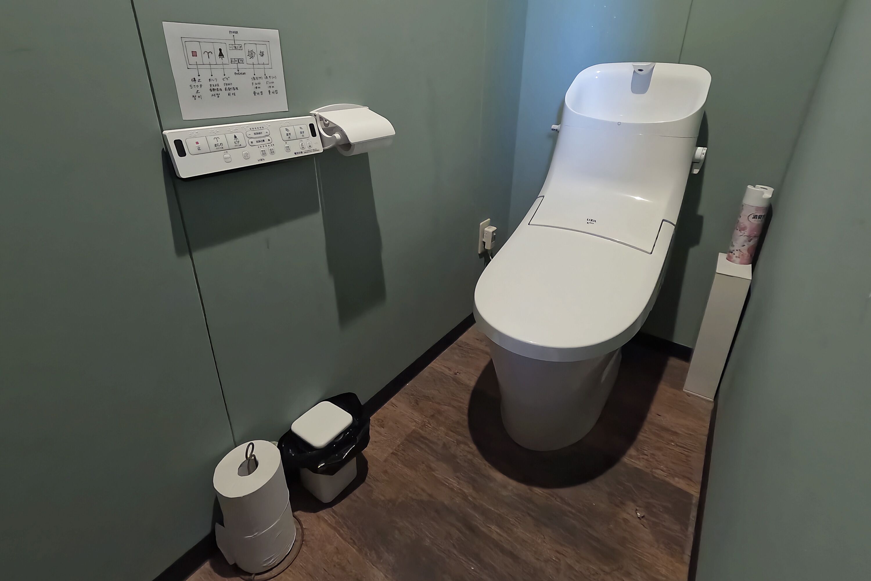 Ein kleines Badezimmer mit Toilette, Papierhandtuchspender, Mülleimer und Toilettenpapierrolle.