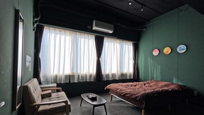 A room with a bed, a chair, a small table, and a window with curtains. - TASOGARE HOSTEL (Hakodate)
