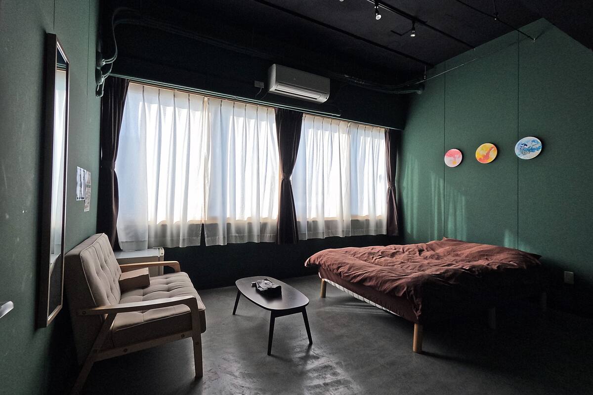 A room with a bed, a chair, a small table, and a window with curtains.