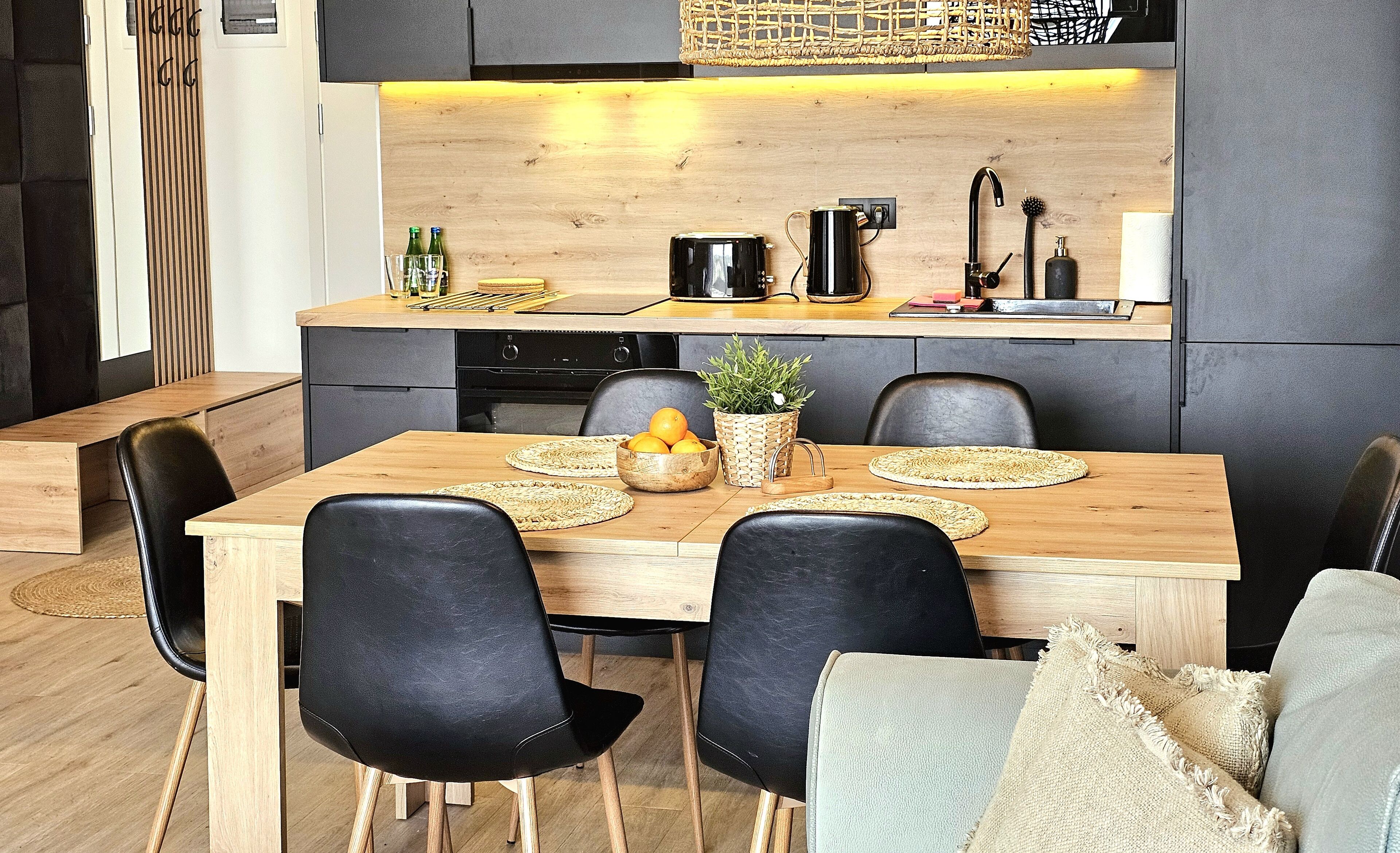 Una cocina moderna con una mesa de madera, sillas negras y una estufa empotrada.