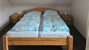 Un letto in legno singolo con testiera, due comodini e una lampada a soffitto.