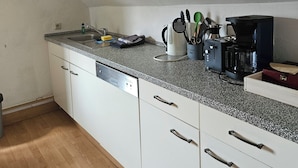 Una cucina con mobili bianchi, un piano di lavoro in granito e una macchina da caffè.