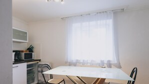 A small, bright kitchen with a white table, two chairs, a microwave, and a coffee maker.