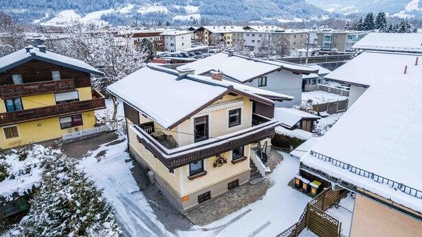 A snow-covered building with a balcony and a staircase leading to the entrance.