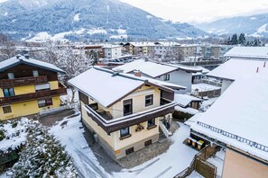A snow-covered building with a balcony and a staircase leading to the entrance. - Areit Apartments - Top 2 (Zell am See)
