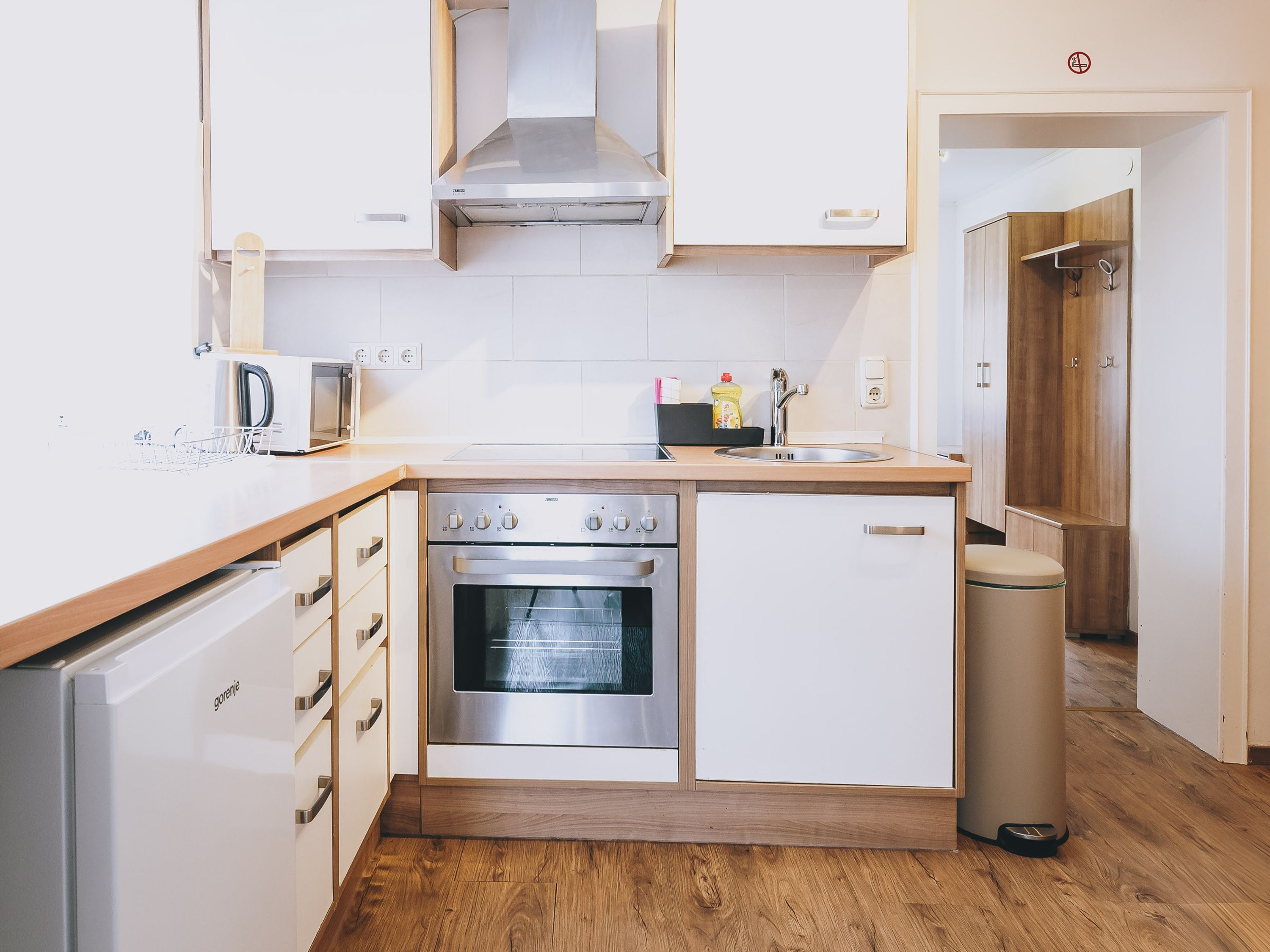 A modern kitchen with white cabinets, a stainless steel oven, and a wooden countertop.