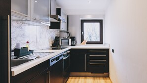 A compact kitchen with a microwave, kettle, and coffee maker on the counter. - Areit Apartments - Top 3 (Zell am See)